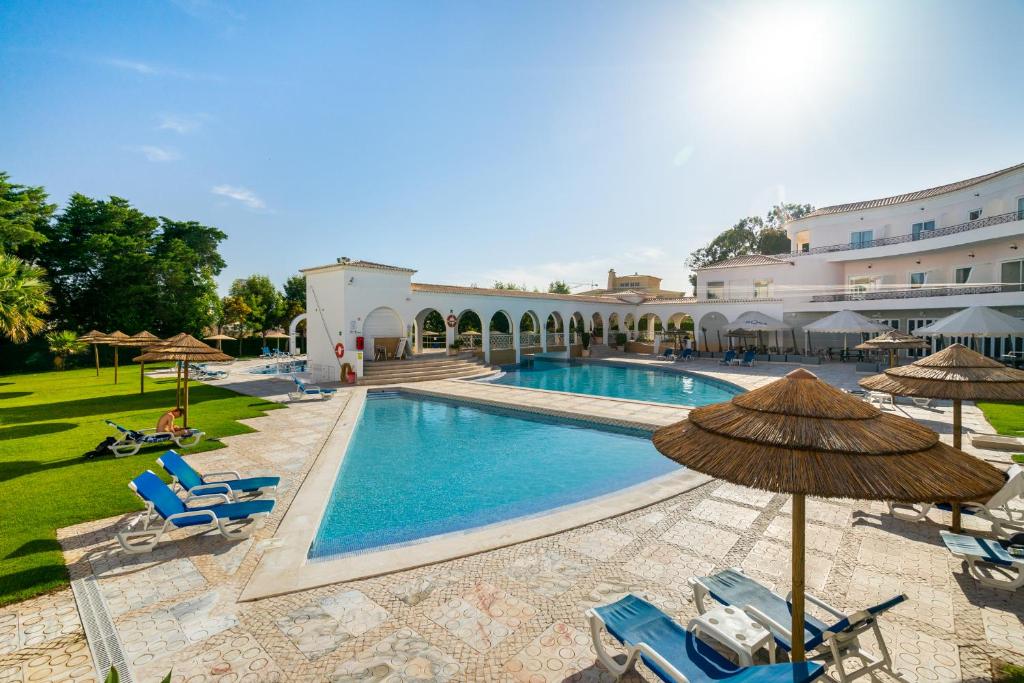 uma piscina com cadeiras e guarda-sóis e um edifício em Vilarosa Oceanside by Encantos do Algarve - 1B em Portimão