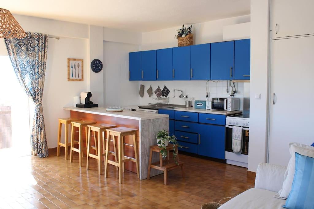 a kitchen with blue cabinets and a counter with bar stools at MAREA Algarve - Sea view sunny apartment in Alvor in Alvor