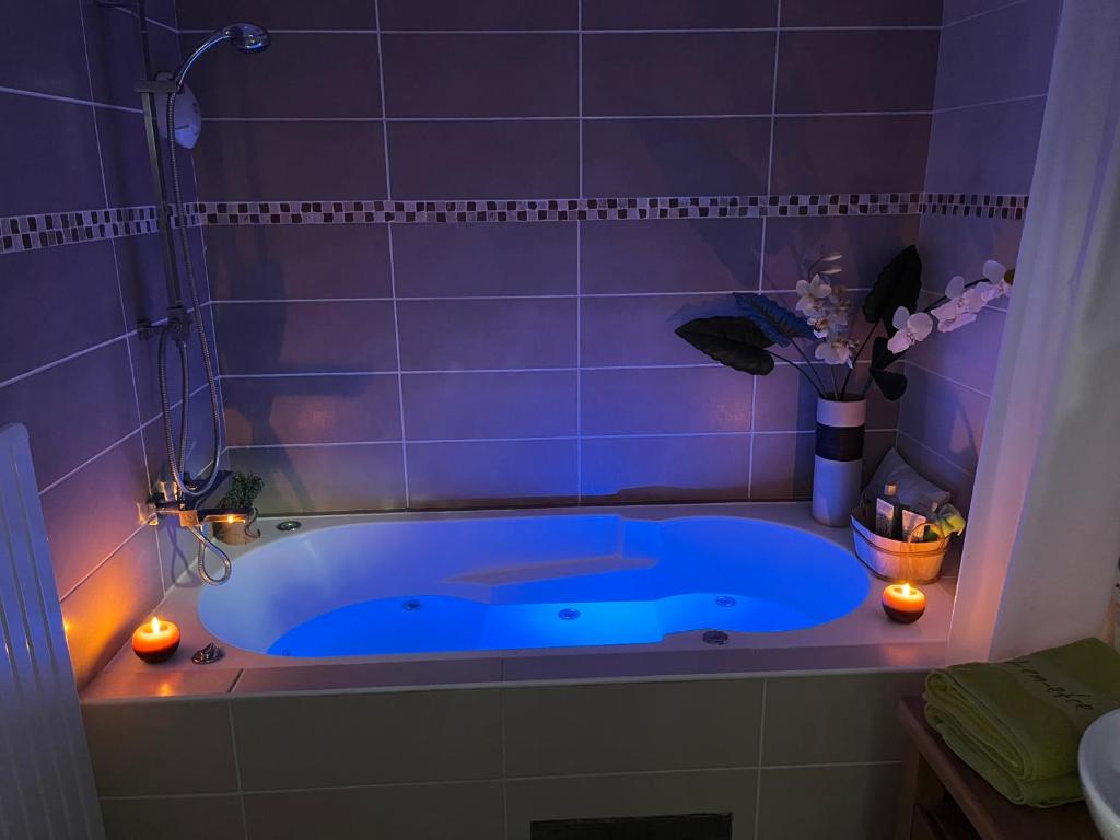 una vasca blu in un bagno con candele e fiori di Loft & Spa LE FAUBOURG SAINT MARTIN a Senlis