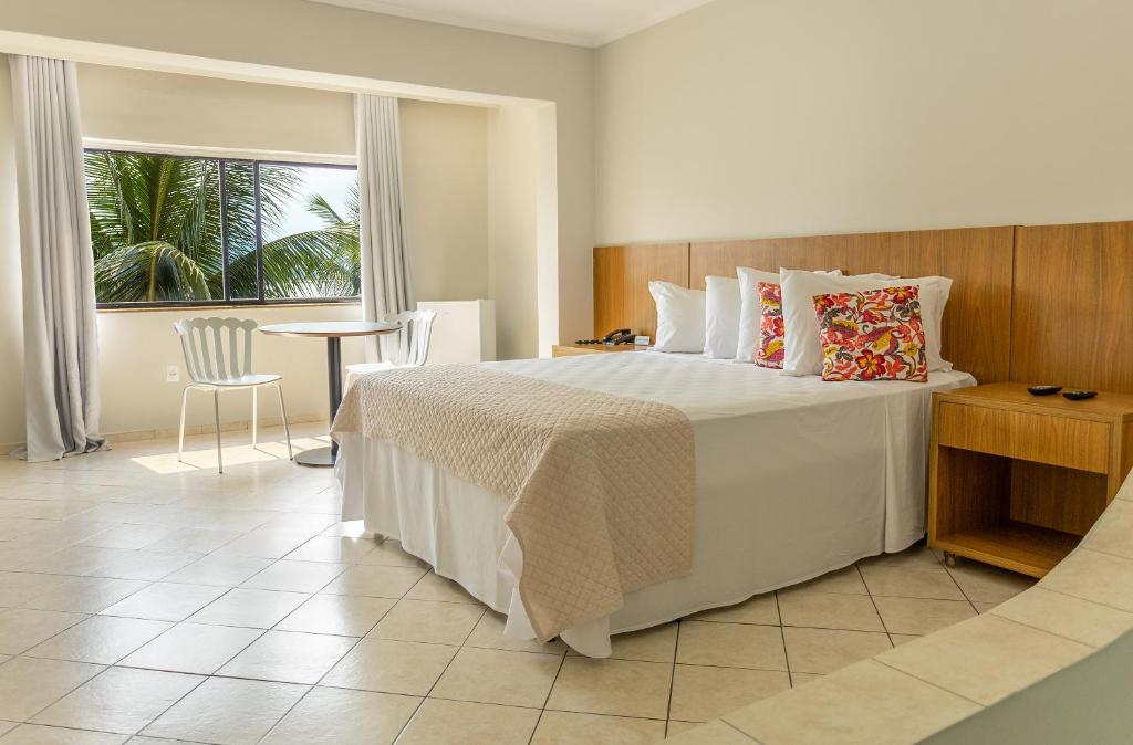 Schlafzimmer mit einem Bett, einem Tisch und einem Fenster in der Unterkunft Ilha Porchat Hotel in São Vicente