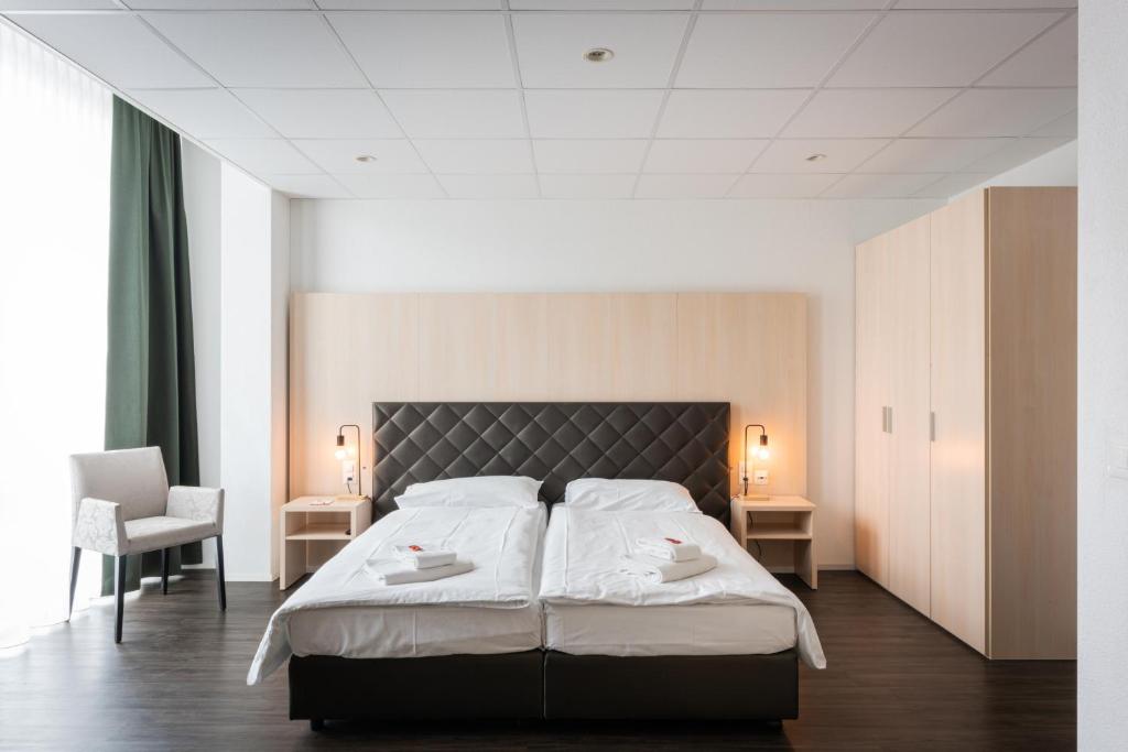 a bedroom with a large bed with two white towels at Los Lorentes Apartments Bern Airport in Belp