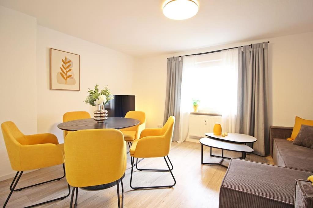 un soggiorno con tavolo e sedie gialle di Blossfeld-Apartments XL-Ferienwohnung Jena Zentrum, 2 Schlafzimmer, W-Lan, Waschtrockner, Smart-TV a Jena