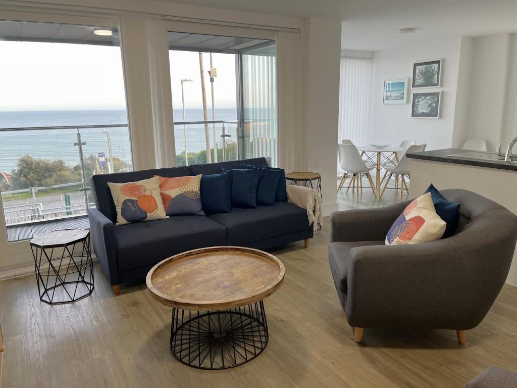 ein Wohnzimmer mit einem Sofa, Stühlen und einem Tisch in der Unterkunft Seaview West Coast in Bournemouth