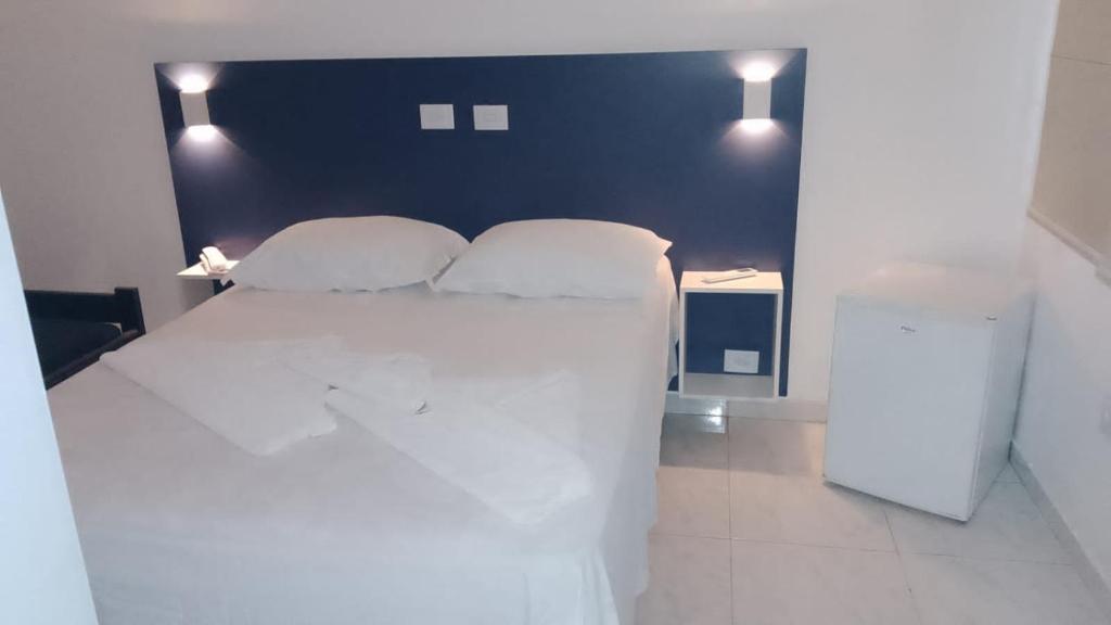 una camera da letto con un grande letto bianco con due cuscini di Hotel Lagoinha a Ubatuba