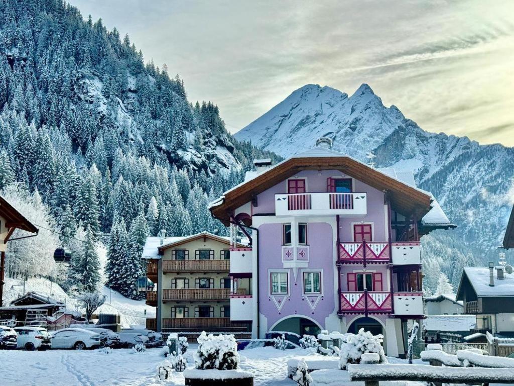 a pink building with a snow covered mountain in the background at Cesa Planber Apartments Mountain View SKI-IN SKI-OUT in Canazei