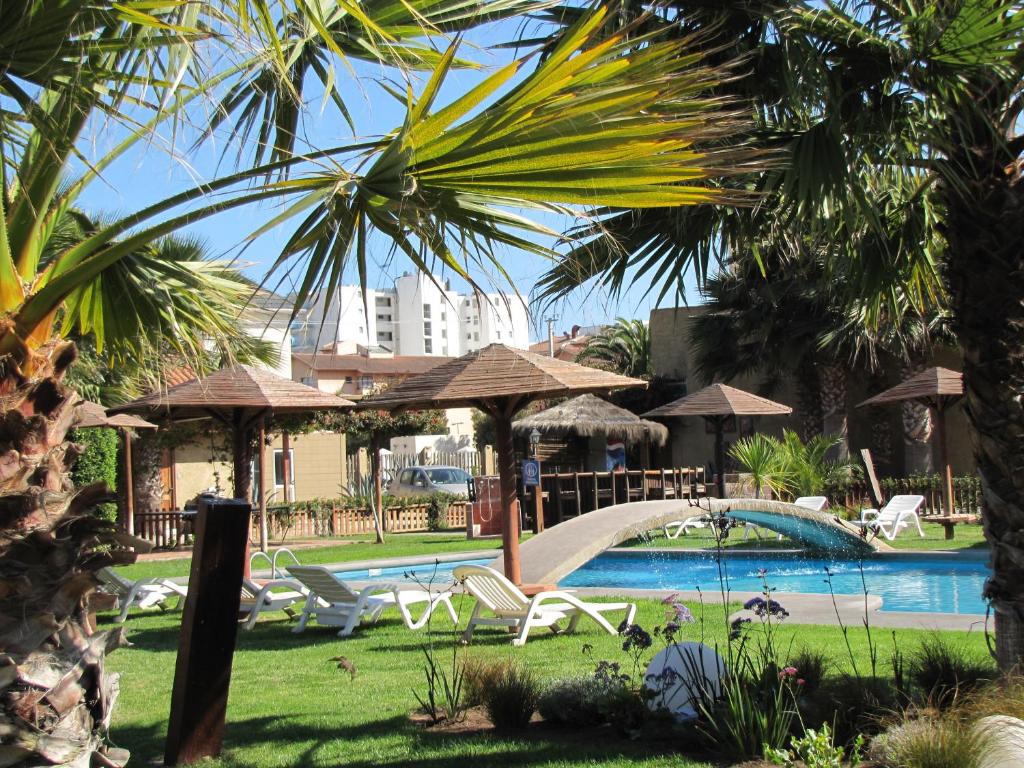 einen Pool mit Stühlen und Sonnenschirmen in einem Resort in der Unterkunft Apart Hotel Gran Pacifico in La Serena