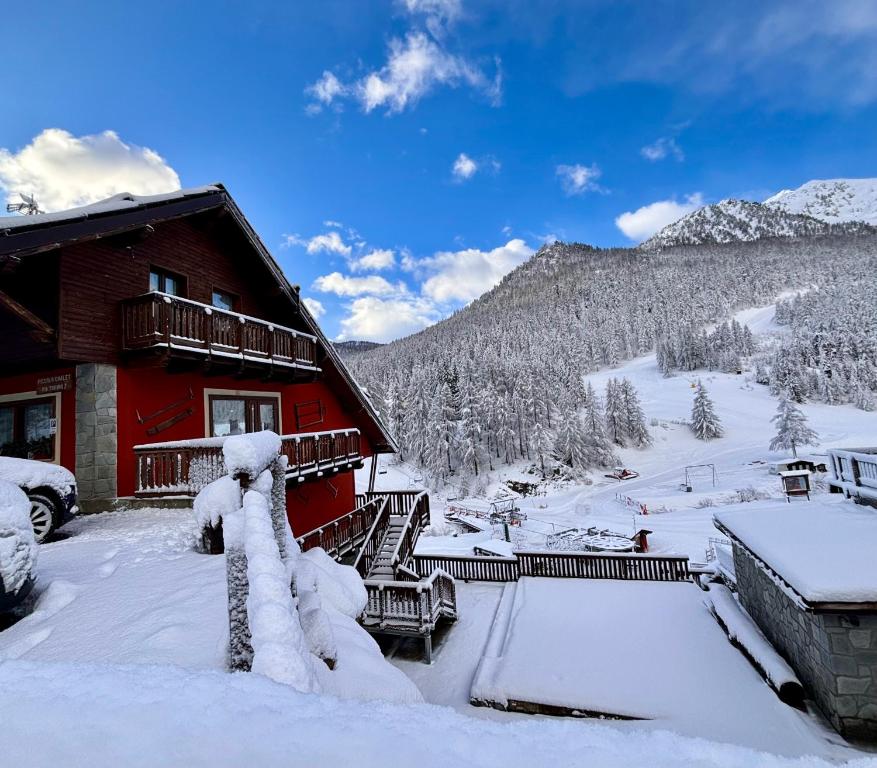 ein Blockhaus im Schnee mit einem Berg in der Unterkunft Hotel Piccolo Chalet in Claviere