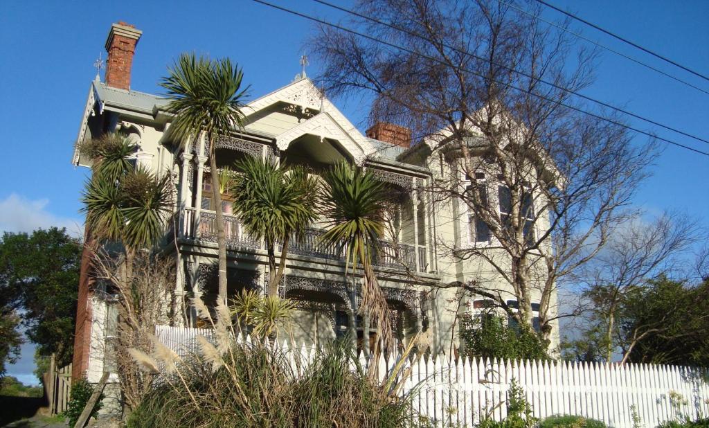 une vieille maison avec une clôture blanche et des palmiers dans l'établissement Artica Art & Accommodation, à Dunedin