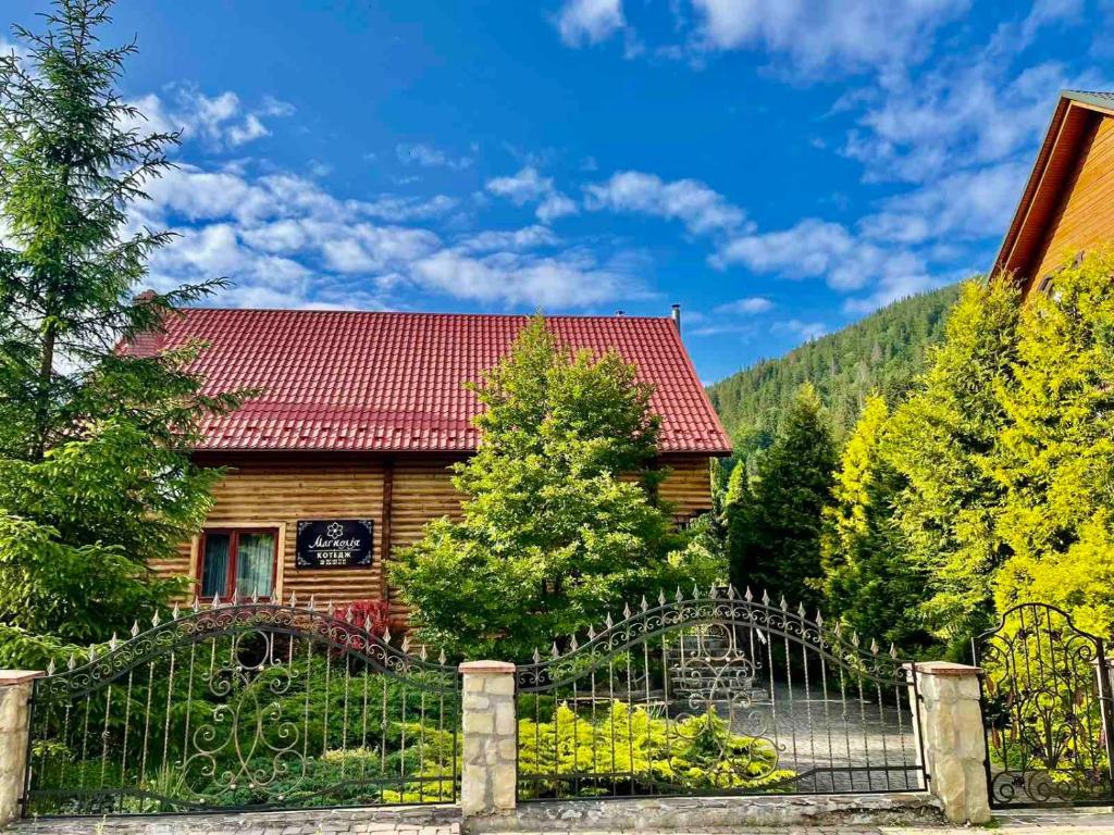 uma casa de madeira com uma cerca em frente em Magnolia em Tatariv