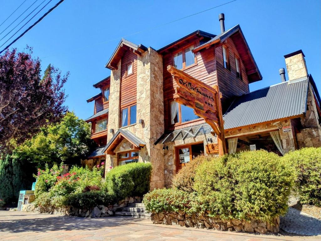 uma grande casa de madeira com arbustos em frente em Apart Hotel Orilla Mansa by Visionnaire em San Martín de los Andes