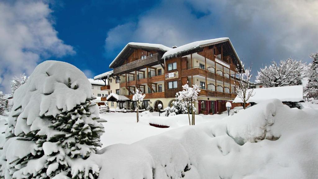 um grande edifício coberto de neve com árvores cobertas de neve em Trail Hotel Oberstaufen em Oberstaufen