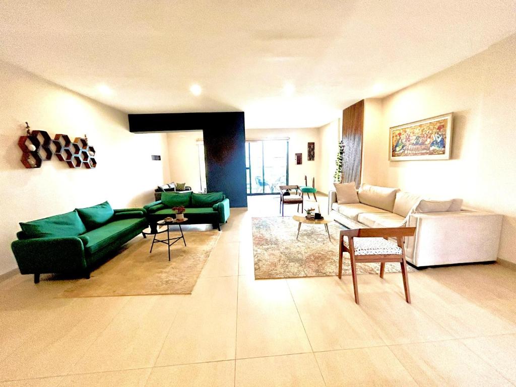 ein Wohnzimmer mit einem grünen Sofa und Stühlen in der Unterkunft Appartement au Almadies( piscine et salle de sport) in Dakar