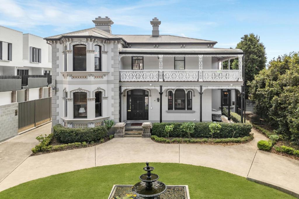 Une grande maison blanche avec une fontaine dans la cour dans l'établissement The Mansion, à Hamilton