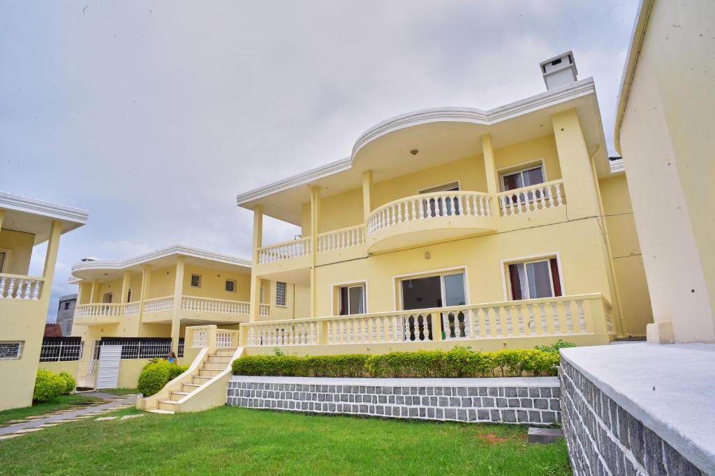 een groot geel gebouw met balkons en een tuin bij Sara Chambre d'hôtes in Antananarivo