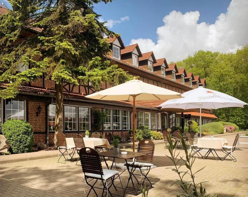 a table and chairs with umbrellas in front of a building at Haags Hotel Niedersachsenhof in Verden