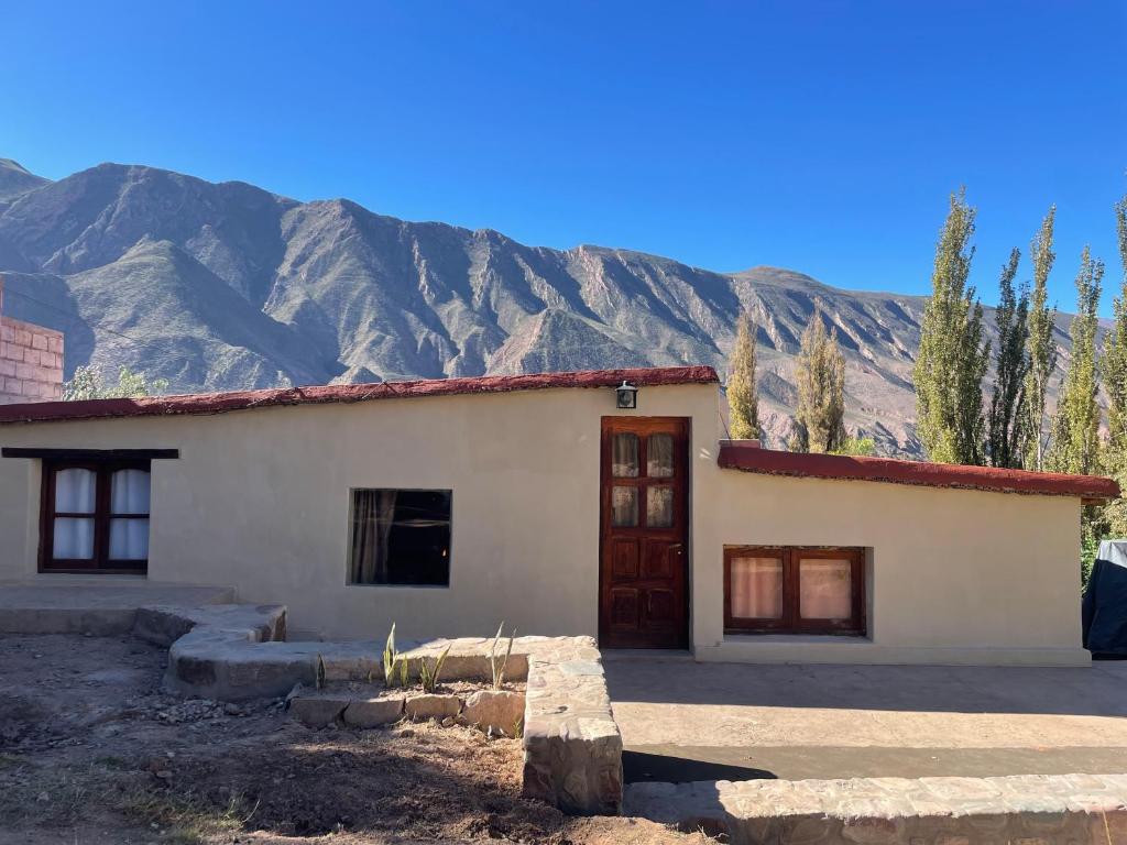 a small white house with mountains in the background at Bello Atardecer in Tilcara