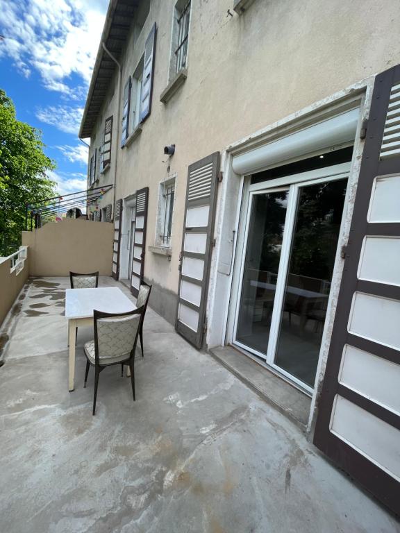 un patio con mesa y sillas junto a un edificio en ALTA, en Bourg-lès-Valence