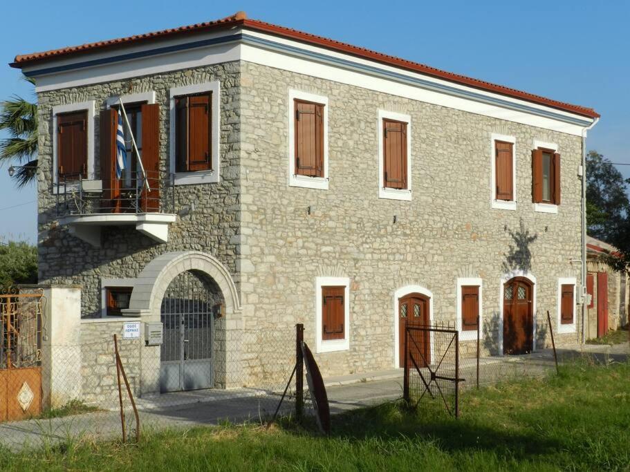 un bâtiment en brique avec une porte devant lui dans l'établissement La Casa di Ercole across bay of Nafplio., à Myloi