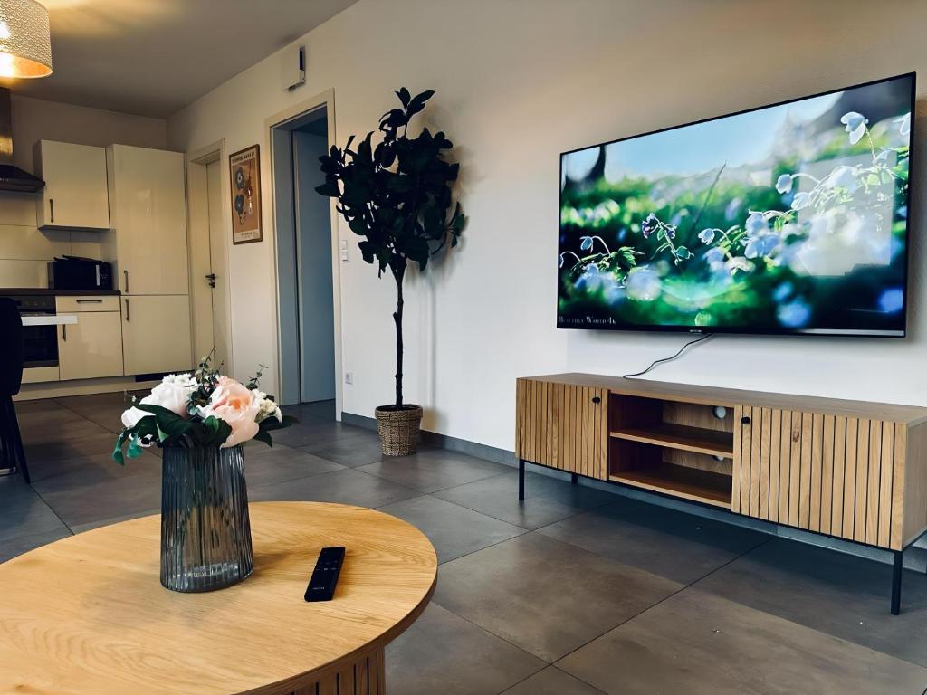 a living room with a tv and a vase of flowers on a table at FeWo Am Povelturm - mit Aufzug und großer Loggia in Nordhorn