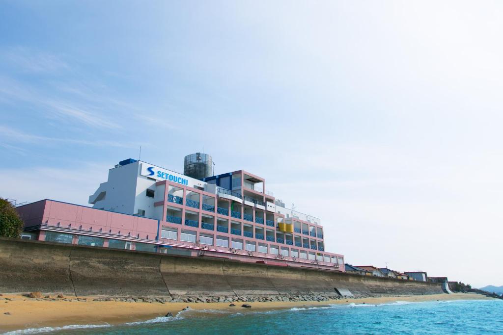 a building on the beach next to the ocean at 瀬戸内リゾートホテル in Matsuyama