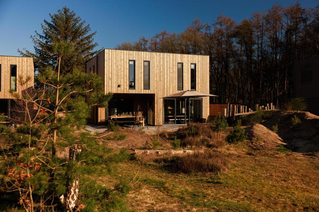 een gebouw op een heuvel met bomen en gras bij Dutchen Zeegser Duinen Villalodges in Zeegse