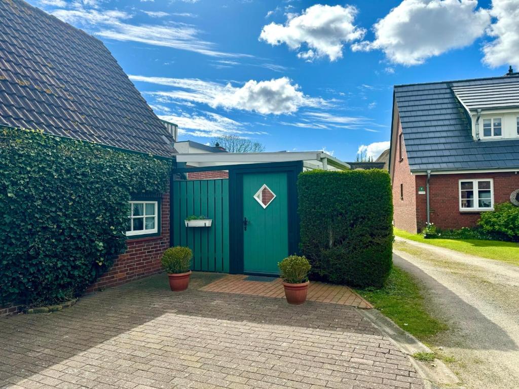 un garage avec une porte verte sur une maison dans l'établissement Nordseestübchen Whg 03, à Nieblum