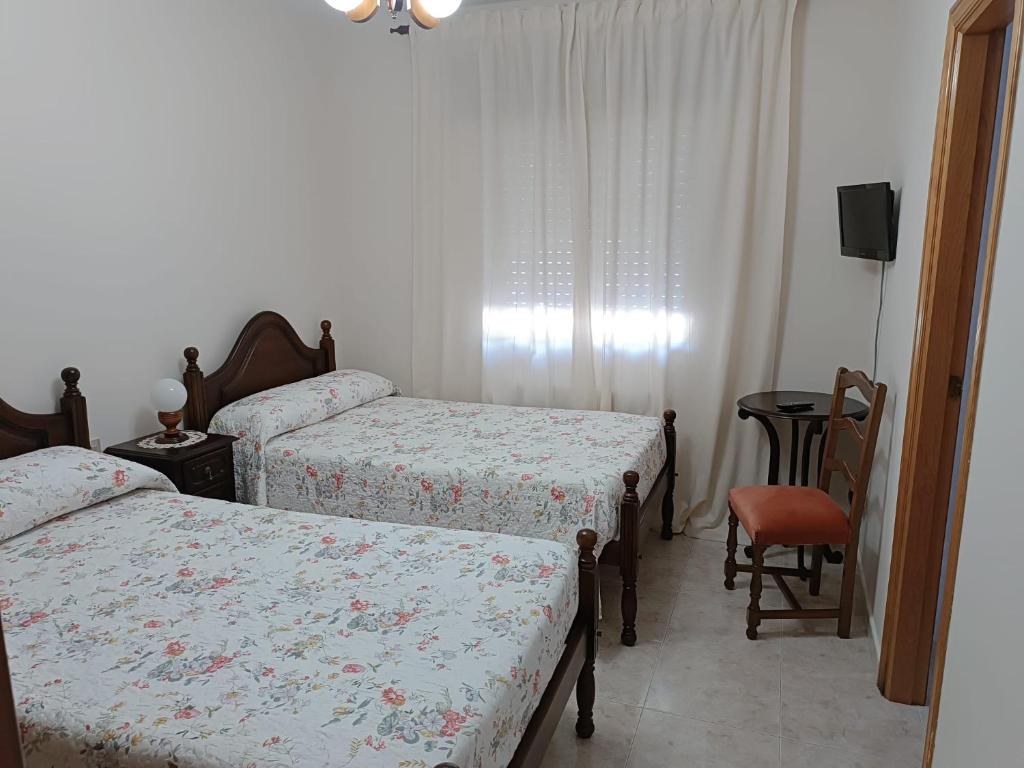 um quarto com 2 camas, uma mesa e uma cadeira em PENSIÓN* AS VIÑAS em Puebla del Brollón