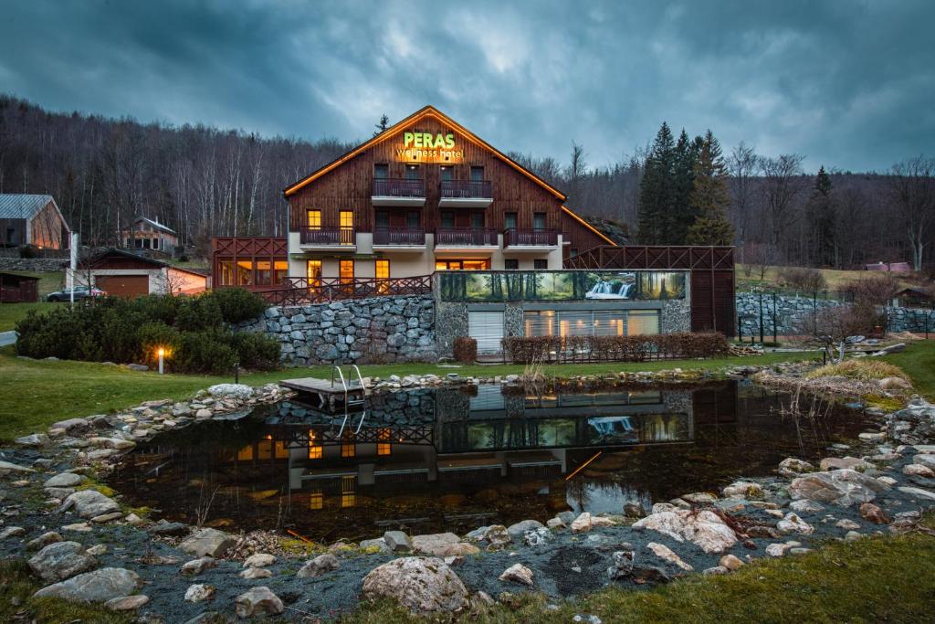 une grande maison avec un étang en face de celle-ci dans l'établissement Peras Wellness Hotel, à Ludvíkov