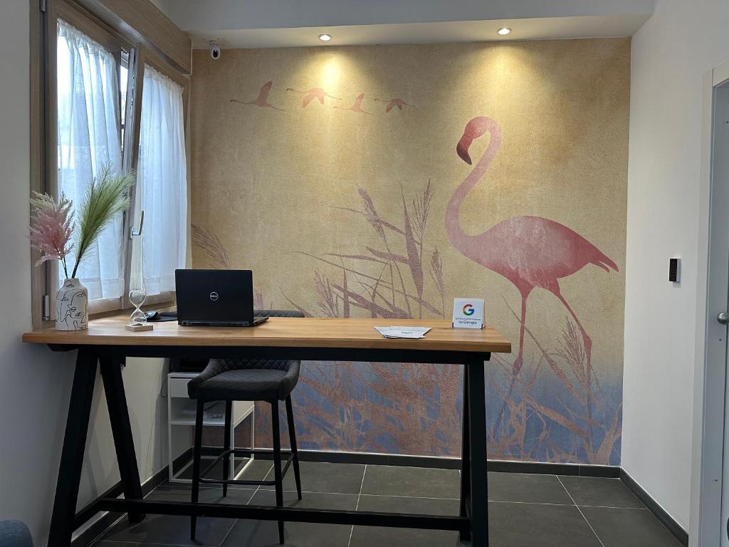 een kamer met een bureau en een flamingo-schilderij aan de muur bij NG Guest House il Gallura in Olbia