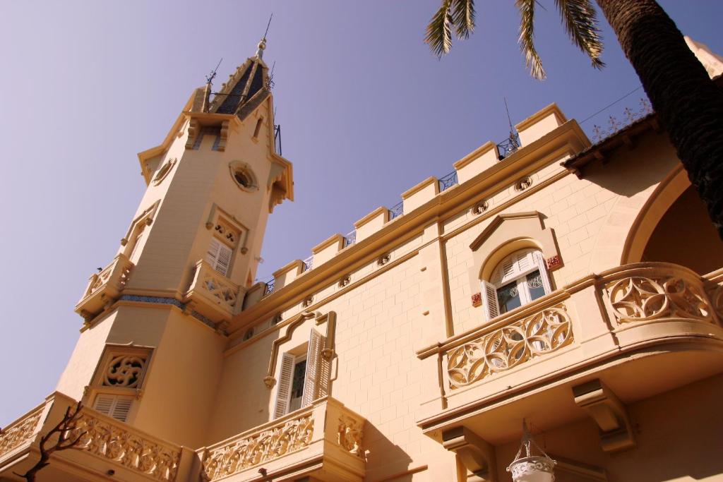 a building with a clock tower and a balcony at Hotel El Xalet in Sitges