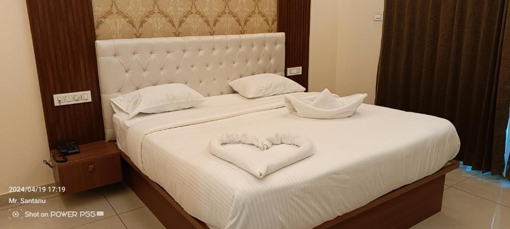 een wit bed met een hartvormig kussen erop bij HOTEL RAMSON'S INTERNATIONAL in Mysore