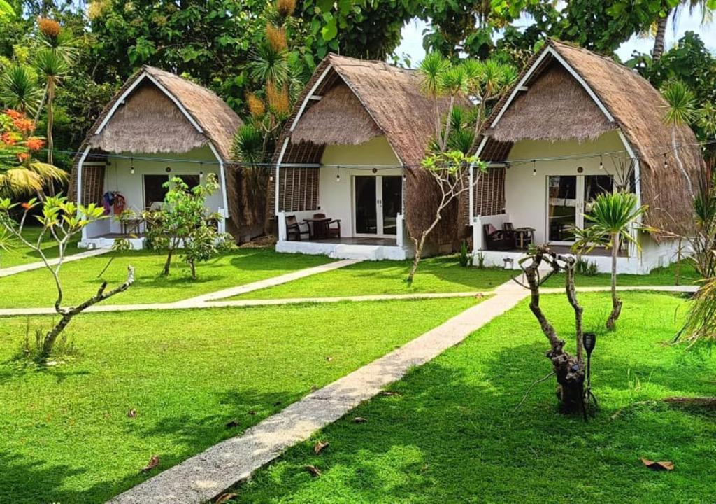 un resort con due cottage in un cortile verde di Namaste Bungalows a Nusa Penida