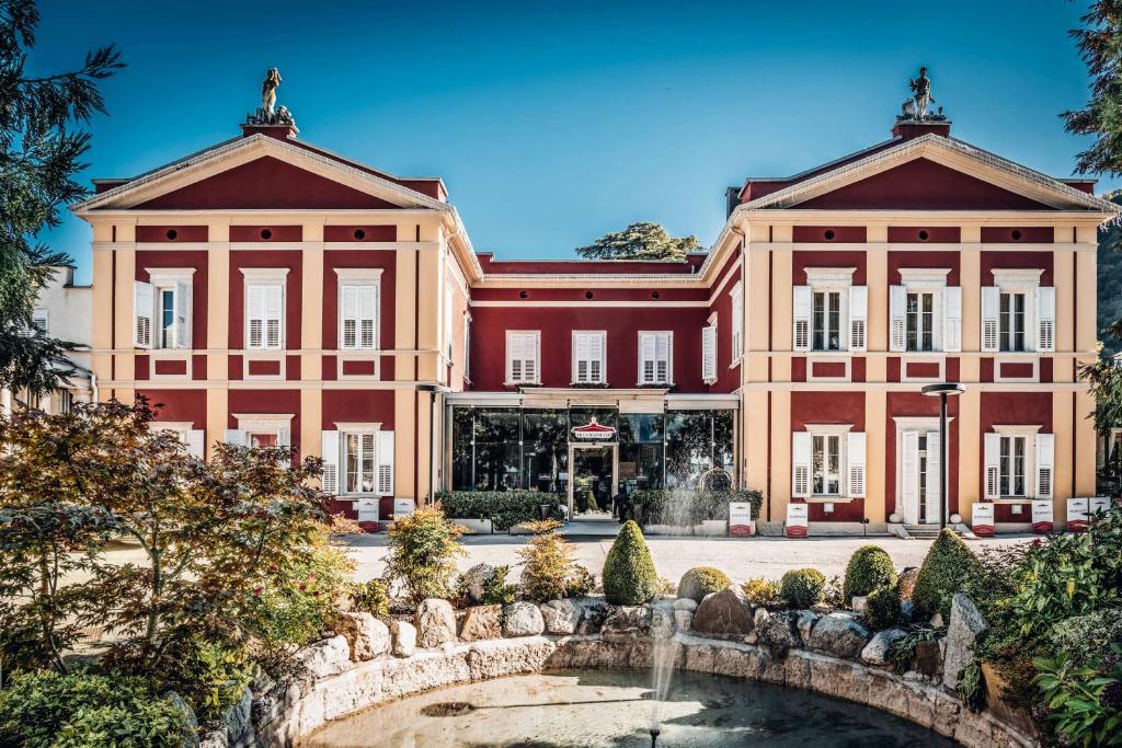 un grande edificio con una fontana di fronte di Hotel Villa Madruzzo a Trento