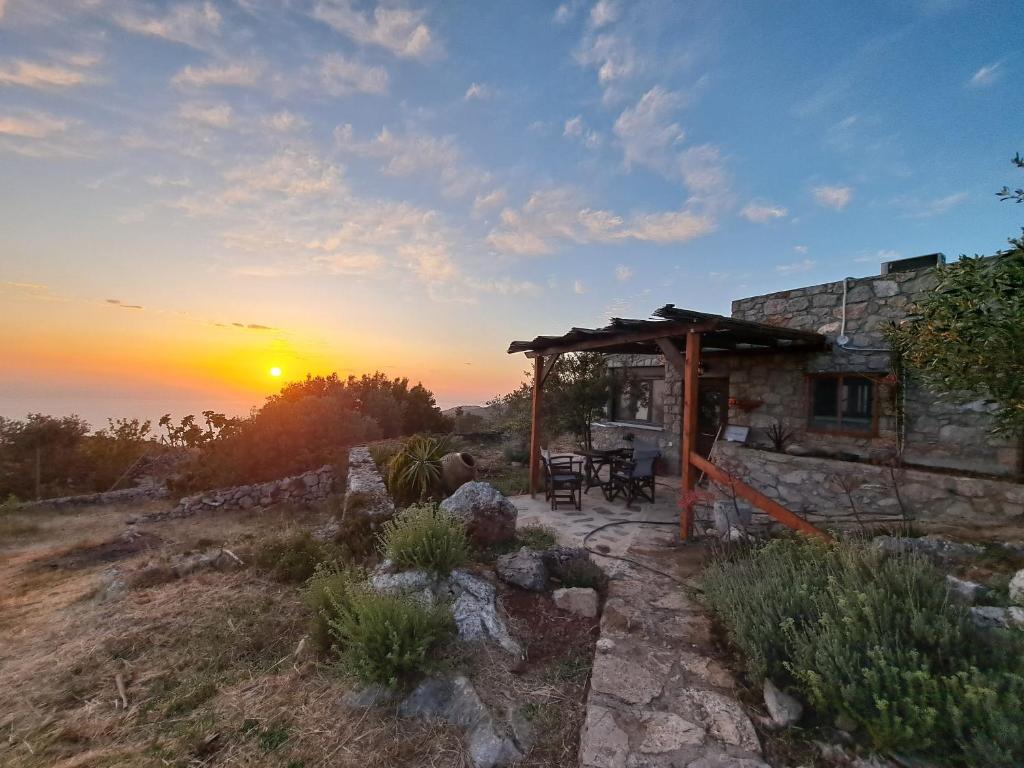 una casa en una colina con la puesta de sol en el fondo en Ηλιοβασίλεμα, en Chios