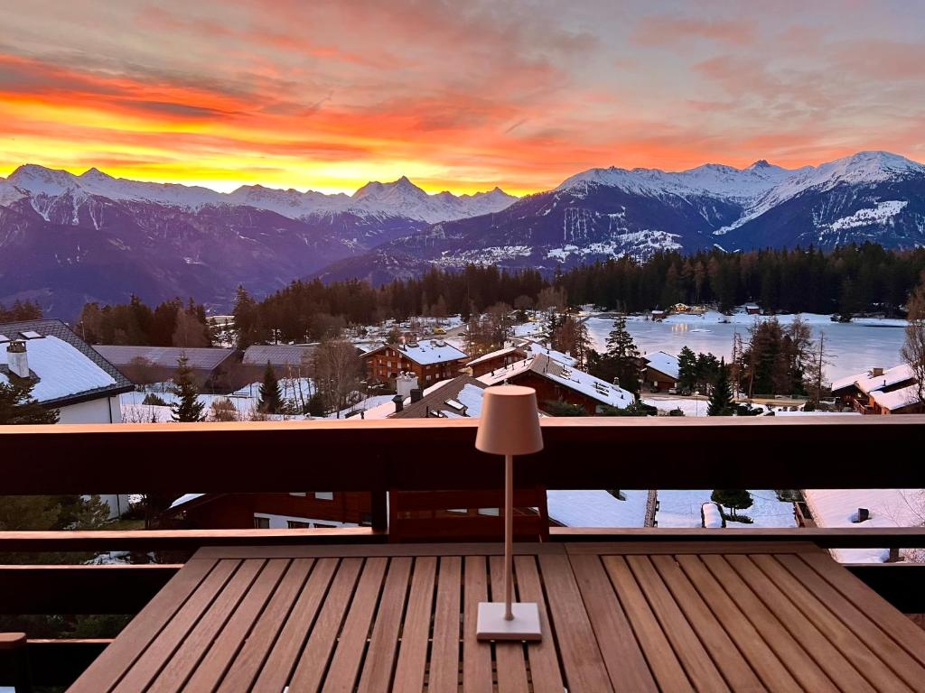 a sunset on a balcony with a view of the mountains at Magnifique attique avec vue sur le lac de la Moubra in Crans-Montana