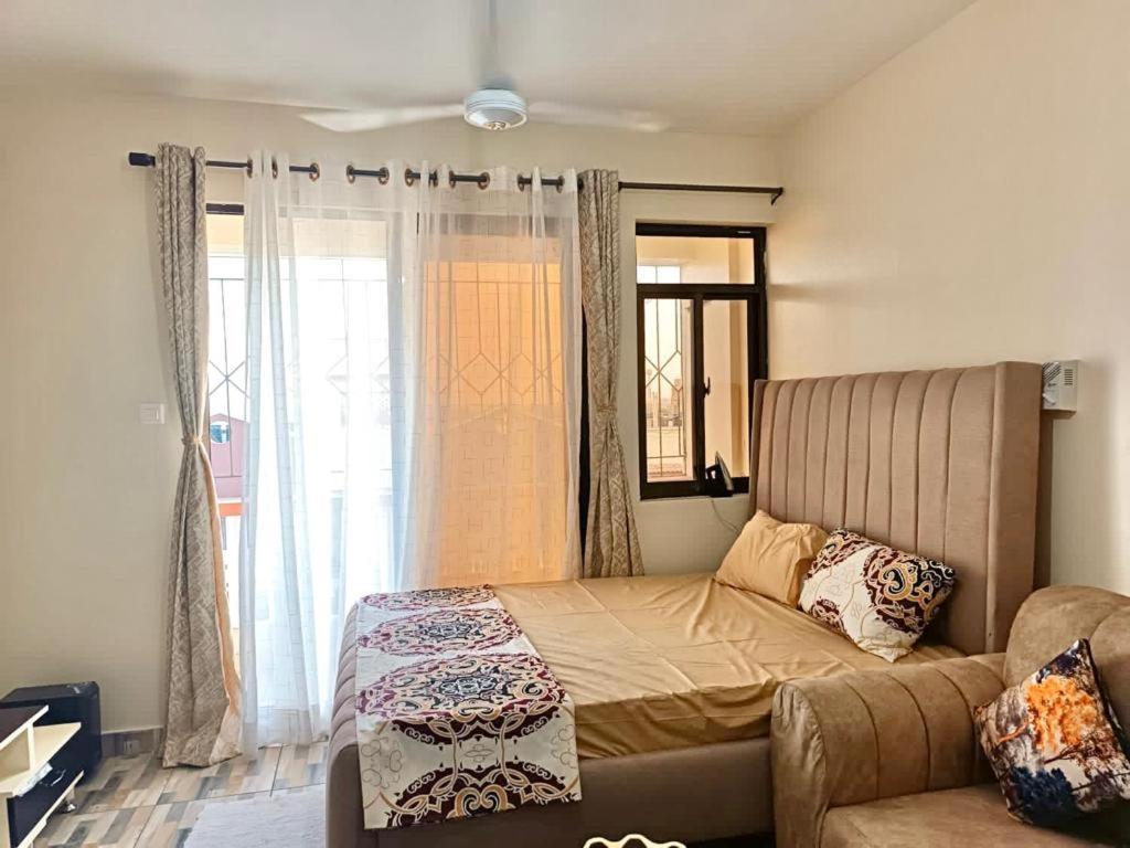 1 dormitorio con cama, sofá y ventana en Homely studio Apartment 2, en Mombasa