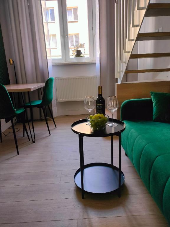 a living room with a green couch and a table with wine glasses at Apartament Paradise Zarządzany przez gospodarza osobę fizyczną Self check in in Rzeszów