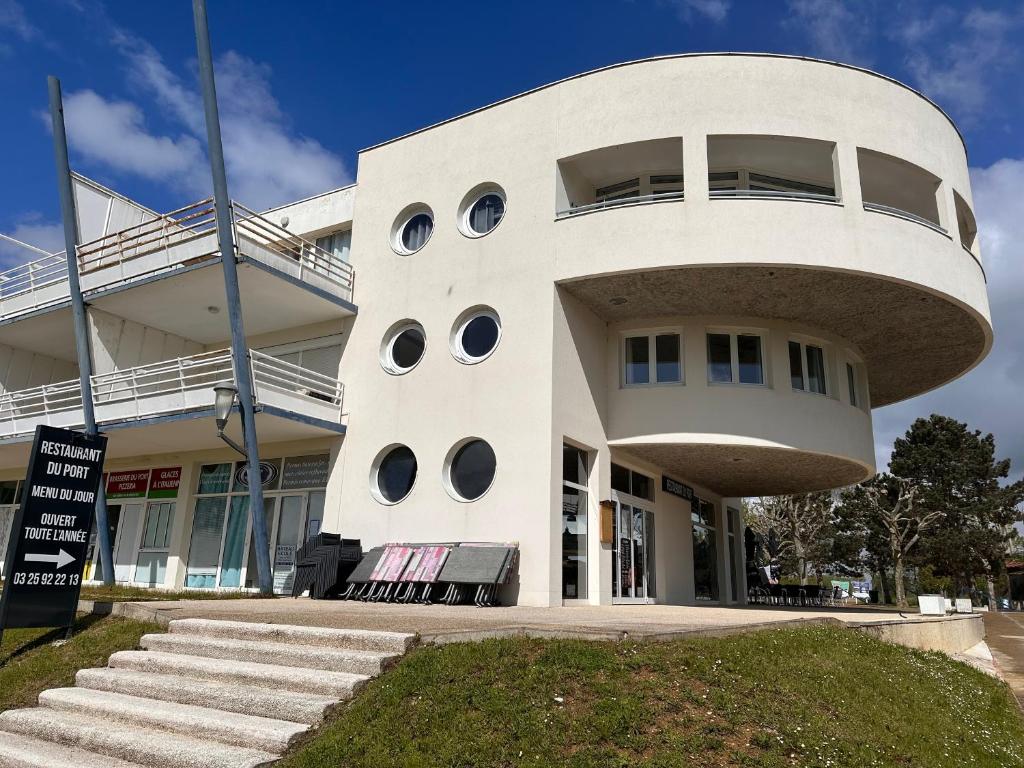 un grand bâtiment blanc avec des fenêtres rondes. dans l'établissement Appartement port dienville, à Dienville