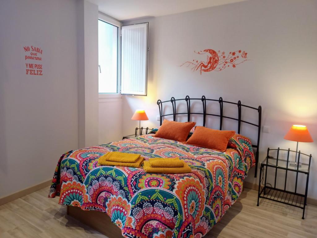 una camera da letto con un letto con un copriletto colorato e due lampade di La Casita de Diana Laredo, Casco Antiguo a Laredo