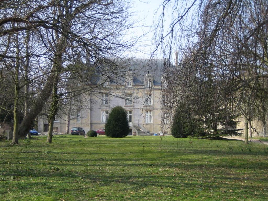 a large building in the middle of a grass field at Chateau de Courseulles in Courseulles-sur-Mer