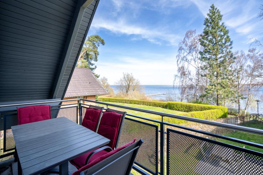 een tafel en stoelen op een balkon met uitzicht op de oceaan bij Strandhaus 2 OG in Röbel