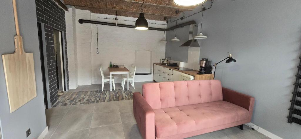 ein Wohnzimmer mit einem rosa Sofa und einer Küche in der Unterkunft Apartamenty STARA PIEKARNIA in Płock