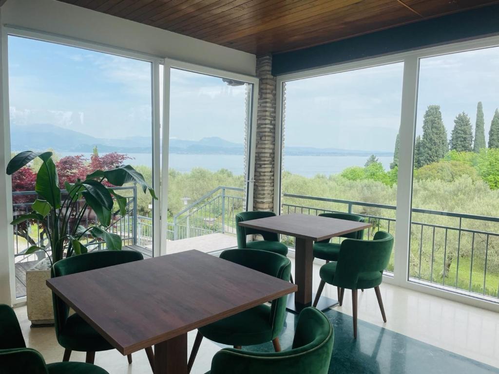 twee tafels en stoelen in een kamer met ramen bij Hotel Mon Repos in Sirmione