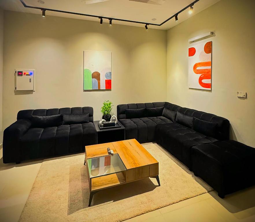 ein Wohnzimmer mit einem schwarzen Sofa und einem Couchtisch in der Unterkunft Central City 2 BHK in Rawalpindi