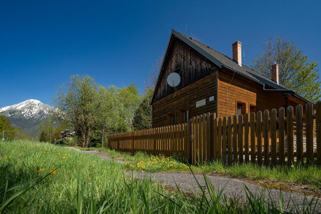 une maison en bois avec une clôture et une montagne dans l'établissement Chata Dolný Smokovec Správa TANAPu, à Dolný Smokovec