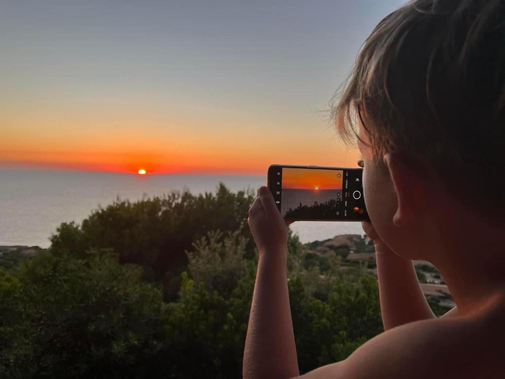 Una donna che scatta una foto al tramonto di Casa Faedda Residence Weber a La Maddalena