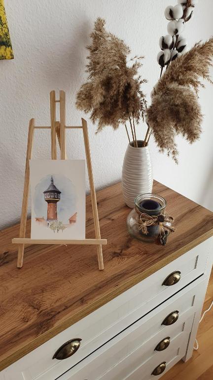 uma cómoda de madeira com uma imagem e um vaso com plantas em Ferienwohnung Karpe em Schwedt