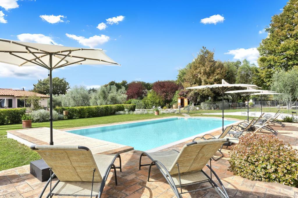 una piscina con sillas y sombrillas en un patio en I Sicomori - Seme di Carota - Glamping e appartamenti con piscina a Saturnia, en Saturnia