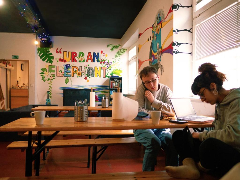 twee mensen aan een tafel met hun laptops bij Urban Elephants Hostel in Bratislava