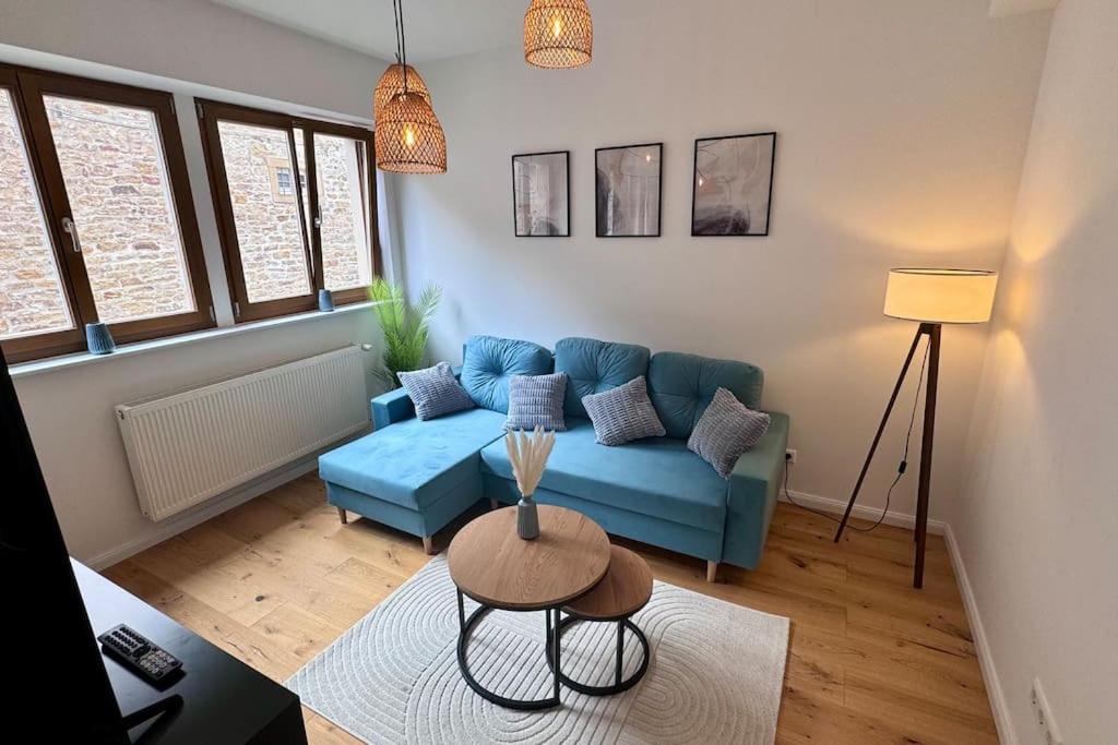 - un salon avec un canapé bleu et une table dans l'établissement Design Apartment im alten Schloss Deidesheim, à Deidesheim